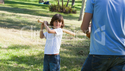 Concentrated little boy playing baseball with his father