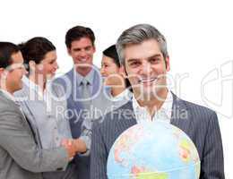 Mature manager holding a terrestrial globe in front of his team