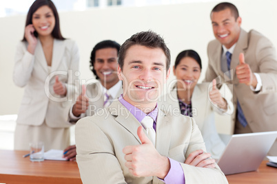 Successful manager in front of his team with thumbs up