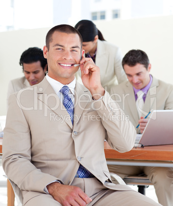 Smiling manager with headset on in front of his team