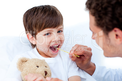 Young doctor taking little boy's temperature