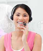 Positive Asian businesswoman talking on headset