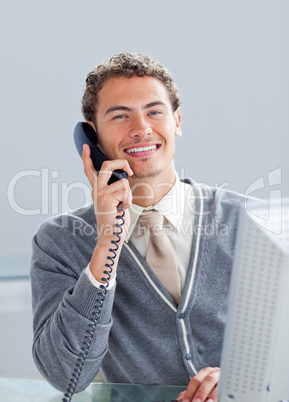 Smiling businessman on phone at his desk