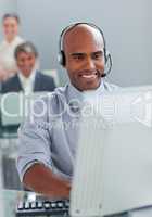 Smiling businessman with headset on working at a computer