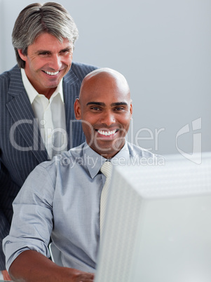 Mature businessman helping his colleague at a computer