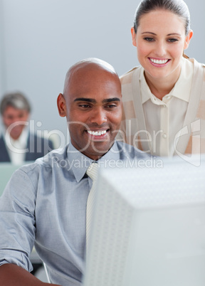 Confident businesswoman helping her colleague at a computer