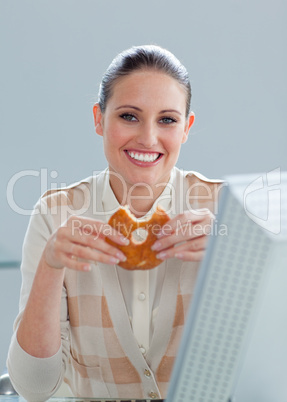 Smiling businesswoman eating a donut