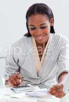 Smiling businesswoman using a calculator at her desk