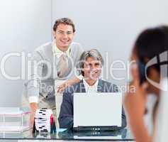 Smiling businessmen working at a computer together