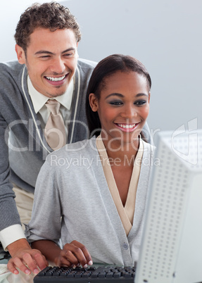 Smiling businessman helping his colleague at a computer