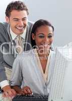 Smiling businessman helping his colleague at a computer