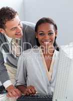 Young businessman helping his colleague at a computer