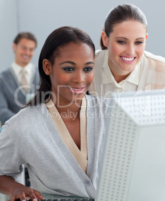 Charming businesswoman helping her colleague at a computer