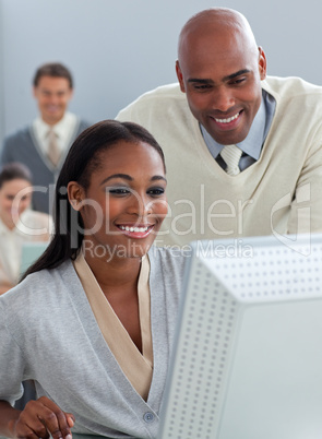 Confident businessman helping his colleague at a computer