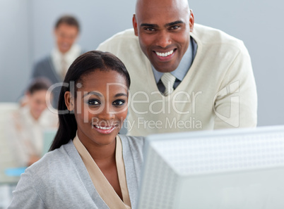 Ethnic businessman helping his colleague at a computer