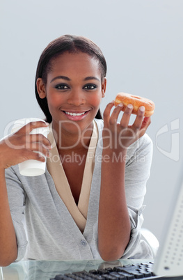 Confident businesswoman eating a donut at her desk