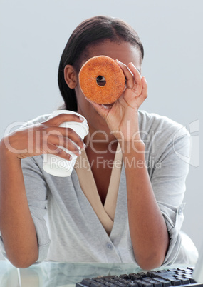 Young businesswoman eating a donut at her desk