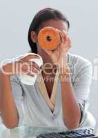 Young businesswoman eating a donut at her desk