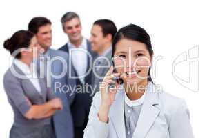 Jolly businesswoman talking on phone in front of her team