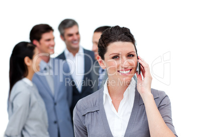 Brunette woman talking on phone in front of her team