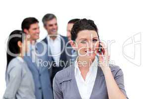 Brunette woman talking on phone in front of her team