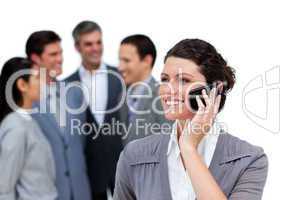 Caucasian woman talking on phone in front of her team