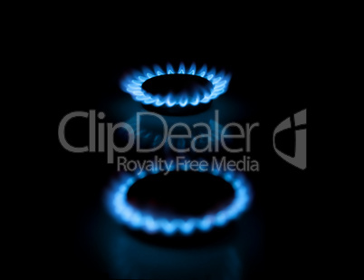 Two gas burners with flames on dark background