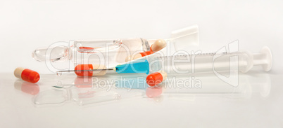 Medical syringe, pills, an ampoule with reflexion