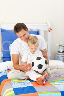 Adorable little boy and his father playing with a soccer ball