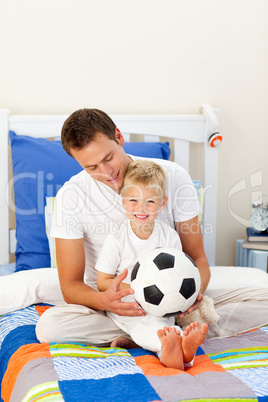 Cute little boy and his father playing with a soccer ball