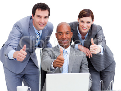 Business people with thumbs up looking at a laptop