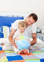 Laughing father and his son looking at a terrestrial globe