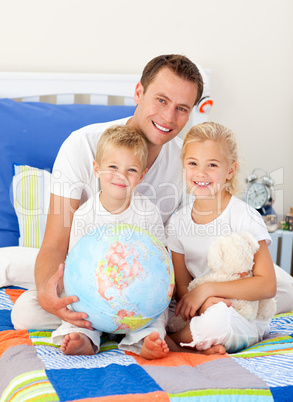 Cute children and their father looking at a terrestrial globe