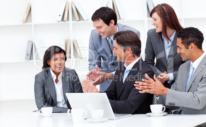 Laughing businesswoman applauded by her team