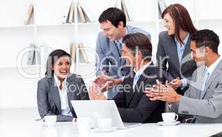 Laughing businesswoman applauded by her team