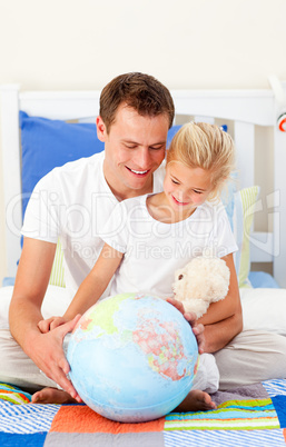 Earing father and his daugther looking at a terrestrial globe