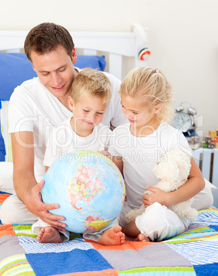 Cute siblings and their father looking at a terrestrial globe