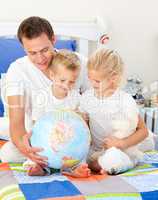 Cute siblings and their father looking at a terrestrial globe