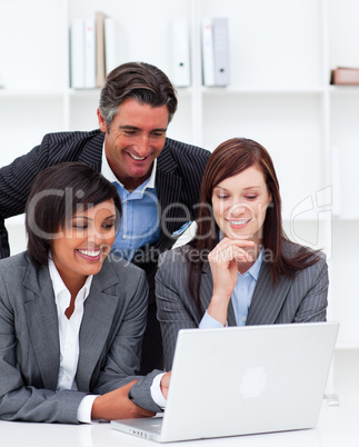 Smiling businesswomen and their colleague working at a laptop