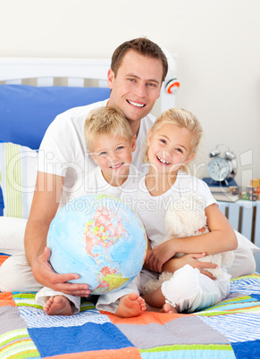 Adorable siblings and their father looking at a terrestrial glob