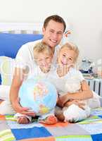 Adorable siblings and their father looking at a terrestrial glob