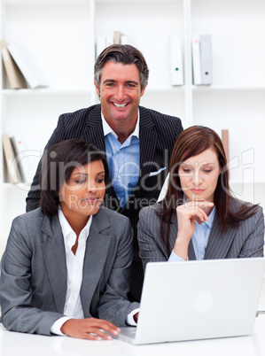 Serious businesswomen and their colleague working at a laptop