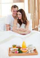 Enamoured couple having breakfast lying in bed