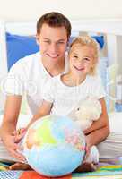 Attentive father and his daugther looking at a terrestrial globe