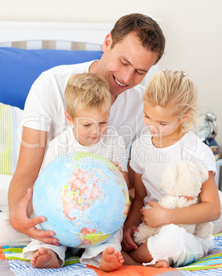 Adorable children and their father looking at a terrestrial glob