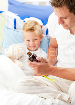 Charming father giving cough syrup to his sick son