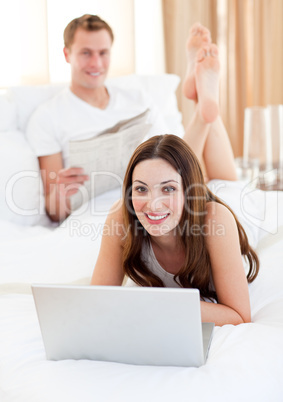 Smiling couple having activites lying on bed