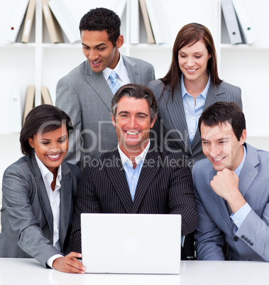 Cheerful business team looking at a laptop