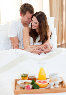 Intimate couple having breakfast lying in bed