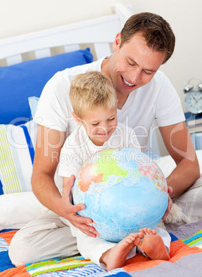 Merry father and his son looking at a terrestrial globe